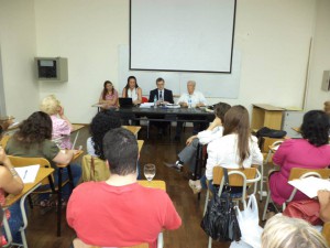 Foto tomada desde atrás del salón, en la cual aparecen los disertantes del segundo panel y los participantes. 